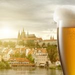 Glass of beer against view of the St. Vitus Cathedral in Prague