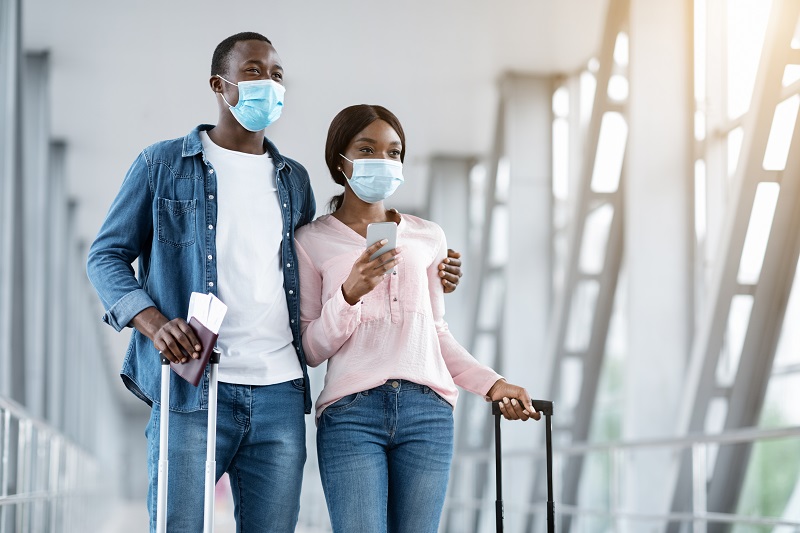 Coronavirus Travels. African American Couple Wearing Protective Medical Masks In Airport Terminal