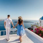 Young,Couple,Holding,Hands,And,Enjoying,View,On,Santorini,Island,