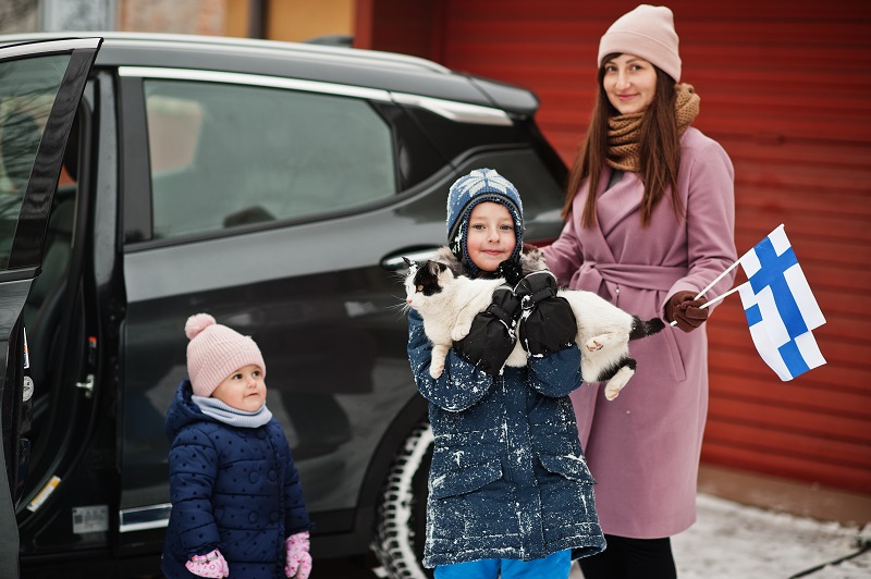 Kids with cat on hands against car in the yard of house at winte