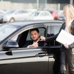 Happy couple buy new modern black car